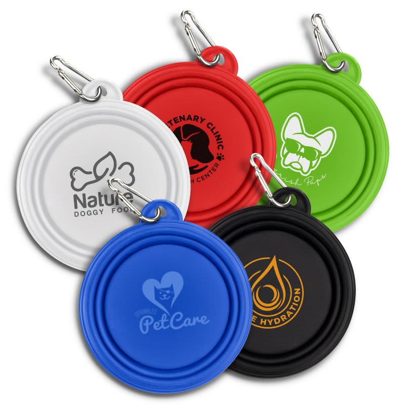 A set of five collapsible silicone pet bowls in blue, red, green, black, and white, featuring various logos. Collapsible Silicone Pet Bowl - Image 1