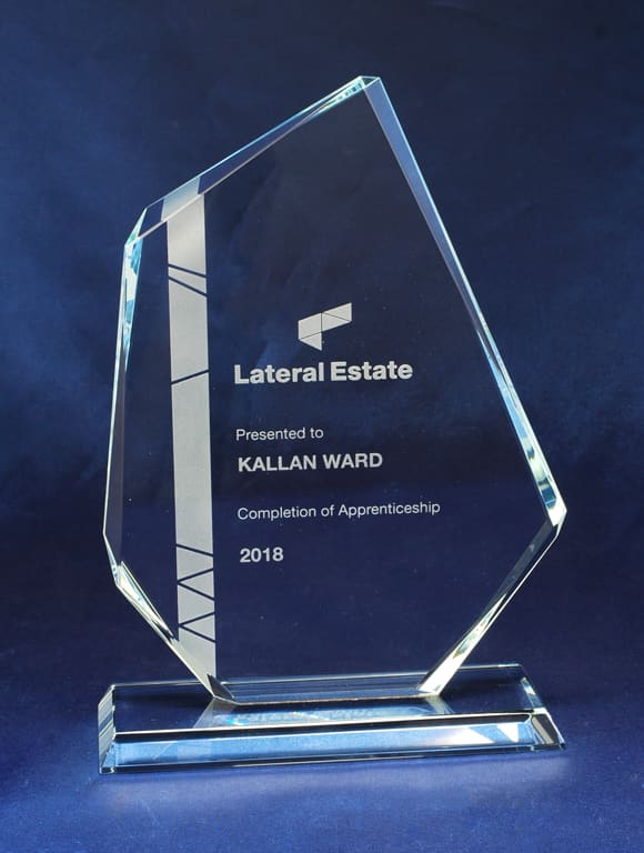A clear glass award with a geometric design, featuring engraved text and a sturdy base. Glass Sail - Image 1