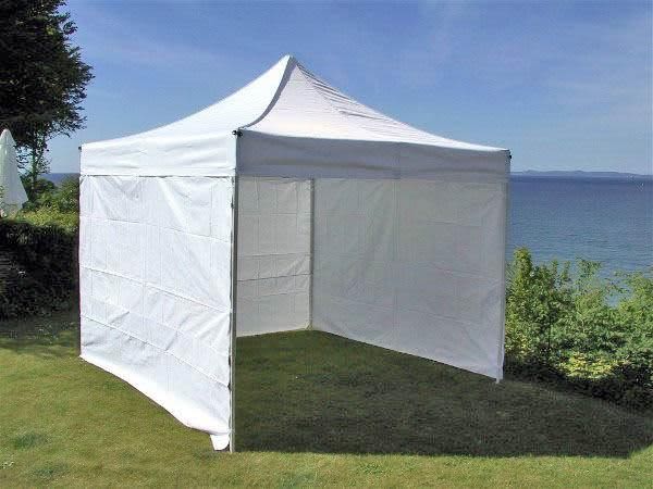 A white marquee tent stands on grass near a lake, featuring a peaked roof and open sides. Marquee Walls Unprinted Wall - 3000 x 2050 mm - Image 1