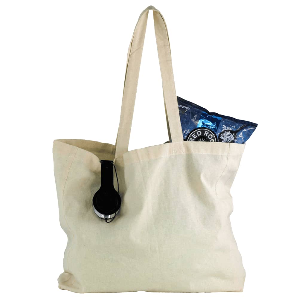 A natural cotton shopper tote in cream, featuring a black headphone and a bag of snacks inside. Natural Cotton Shopper Tote - Image 1