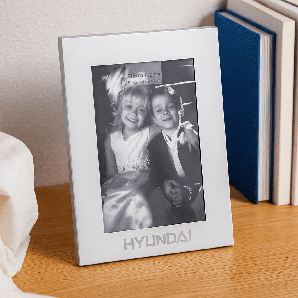 A silver aluminium photo frame displaying a black-and-white photo of two children. The frame features a logo at the bottom. Classic Aluminium Photo Frame - Image 1