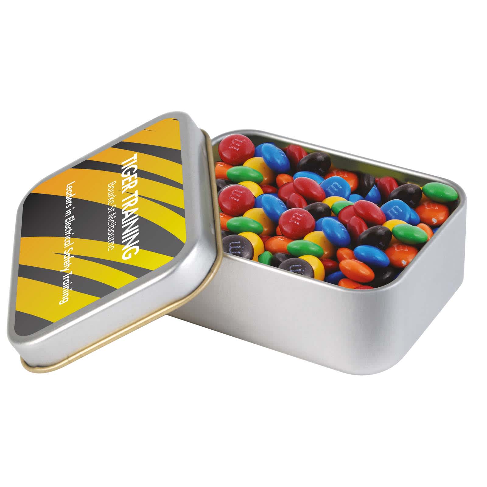 A silver rectangular tin filled with colorful M&M's, featuring a black and yellow design on the lid. M&M's in Silver Rectangular Tin - Image 1