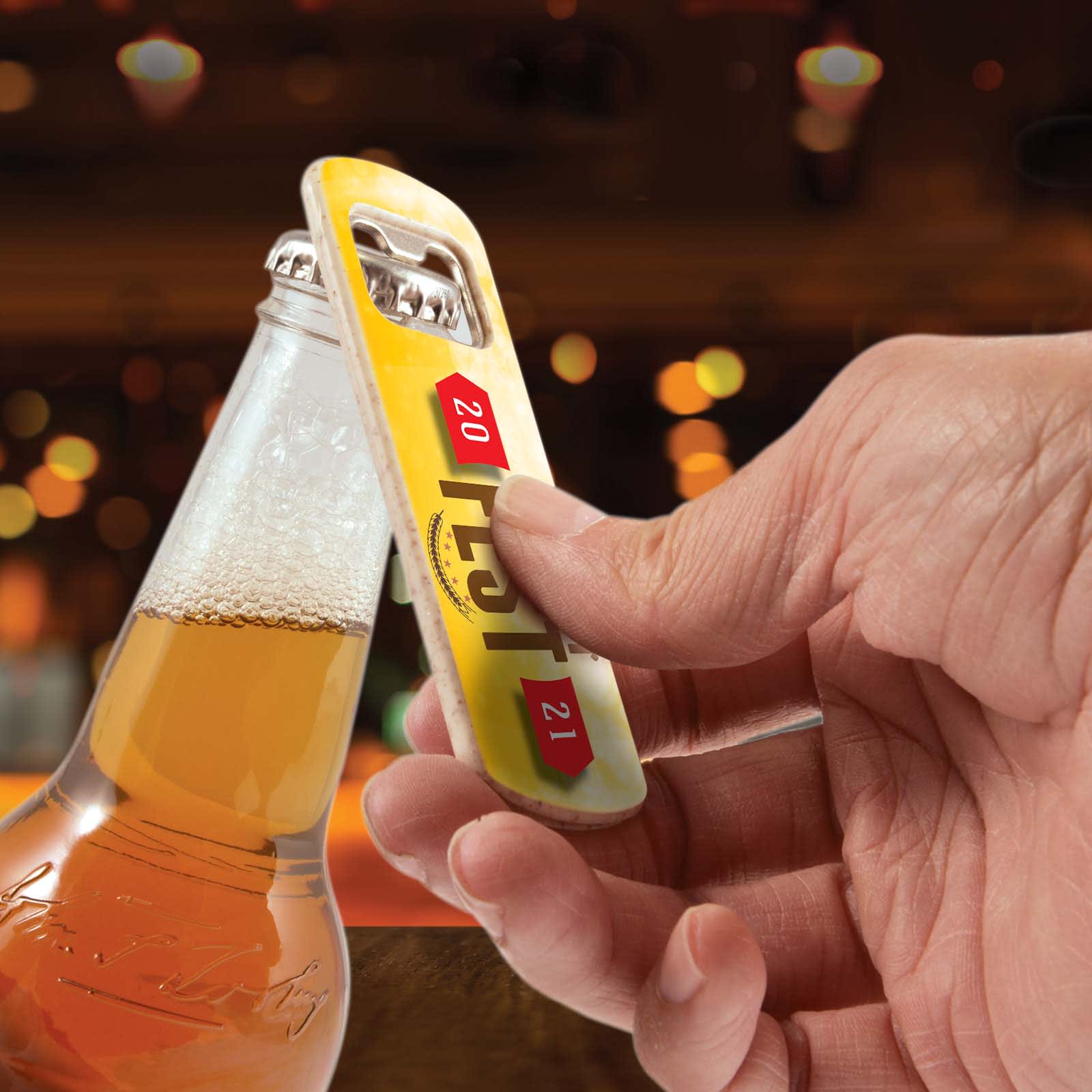 A drink bottle opener with a metallic finish and a yellow handle, held above a beer bottle. Arctic Bottle Opener - Image 1