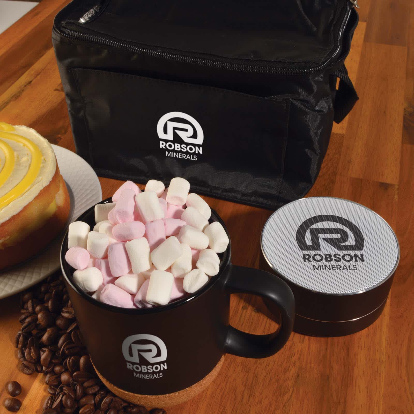 A black coffee mug filled with pink and white marshmallows, next to a silver container and a black bag with a logo. Espresso Coffee Cup and Speaker Pack - Image 1