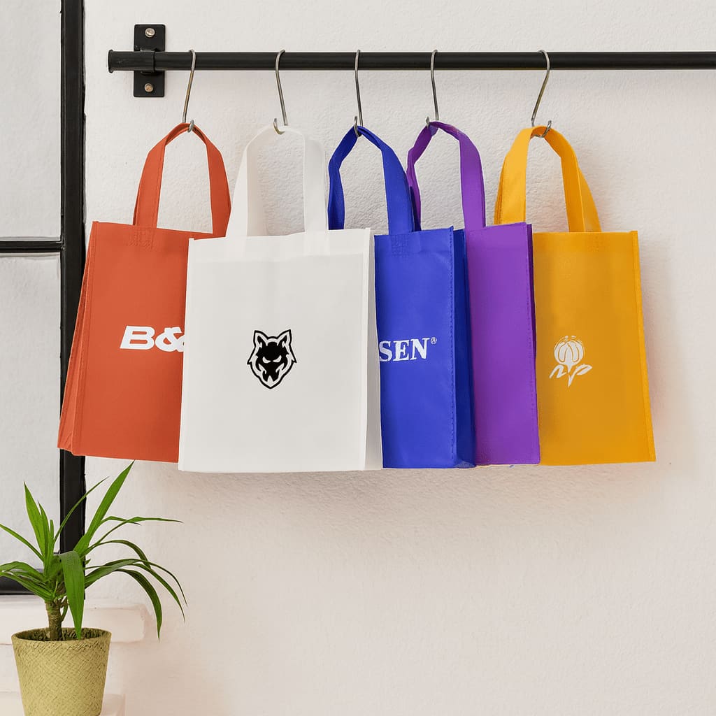A black tote bag with a red stripe and branding, featuring long handles for easy carrying. Tradeshow Bag - Image 1