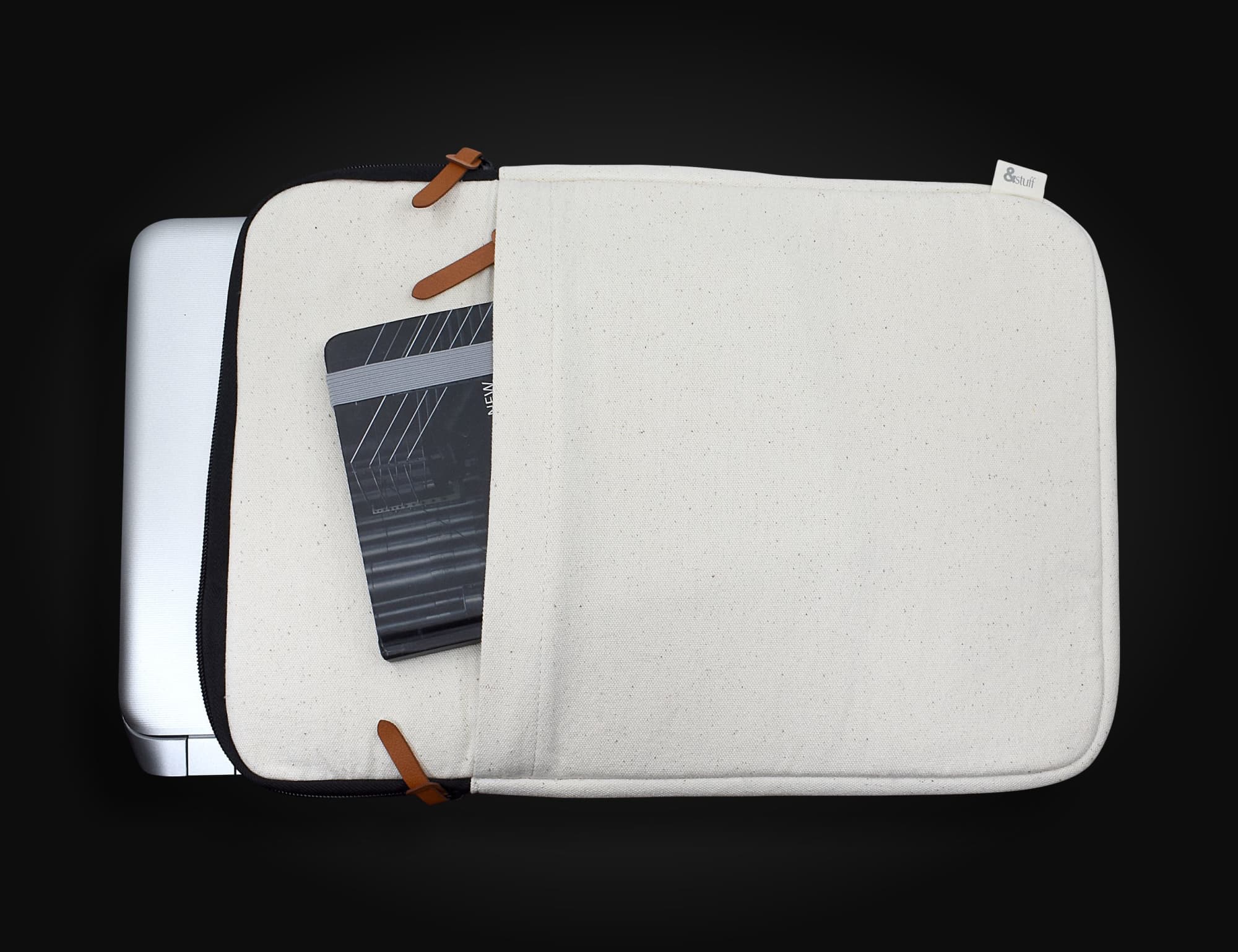 A cream-coloured laptop sleeve with leather accents, showing a partially open compartment and a notebook inside. Calico 15" Laptop Sleeve 27.5 x 40 x 3cm - Image 1