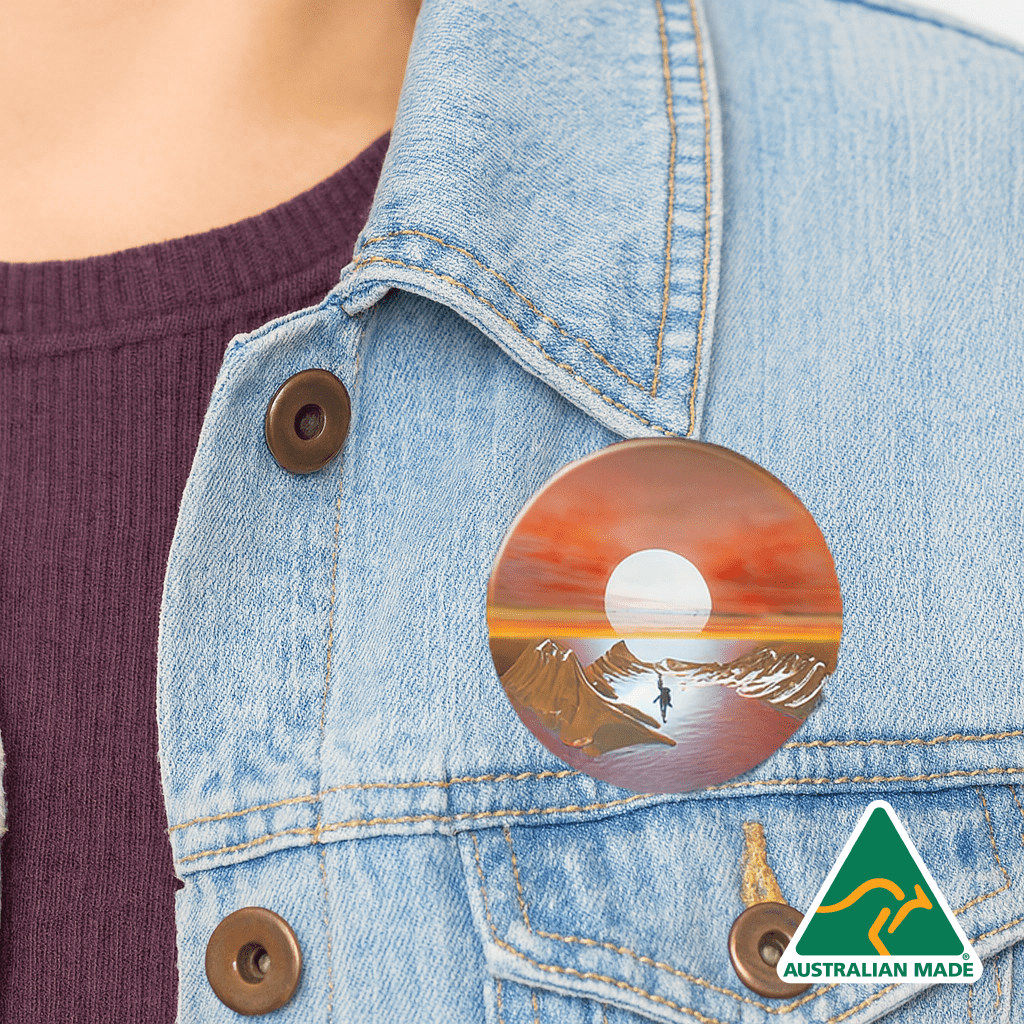 A 65mm button badge with a sunset design, featuring warm colours, attached to a denim jacket. It includes an Australian Made logo. Button Badge 65mm - Image 1