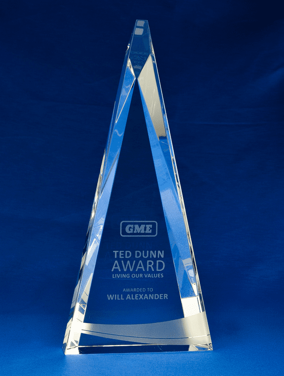 A crystal trophy in the shape of a tall triangle with a logo, featuring engraved award details. Crystal Triangle - Small + Gift Box - Image 1