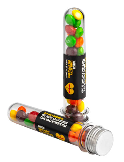 A clear test tube filled with colourful Skittles, featuring a silver cap and a branding label. Test Tube with Skittles 40g - Image 1