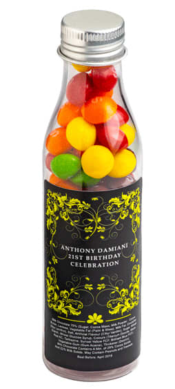 A drink bottle filled with colourful Skittles, featuring a metallic silver cap and decorative black and yellow label. Soda Bottle with Skittles 100g - Image 1
