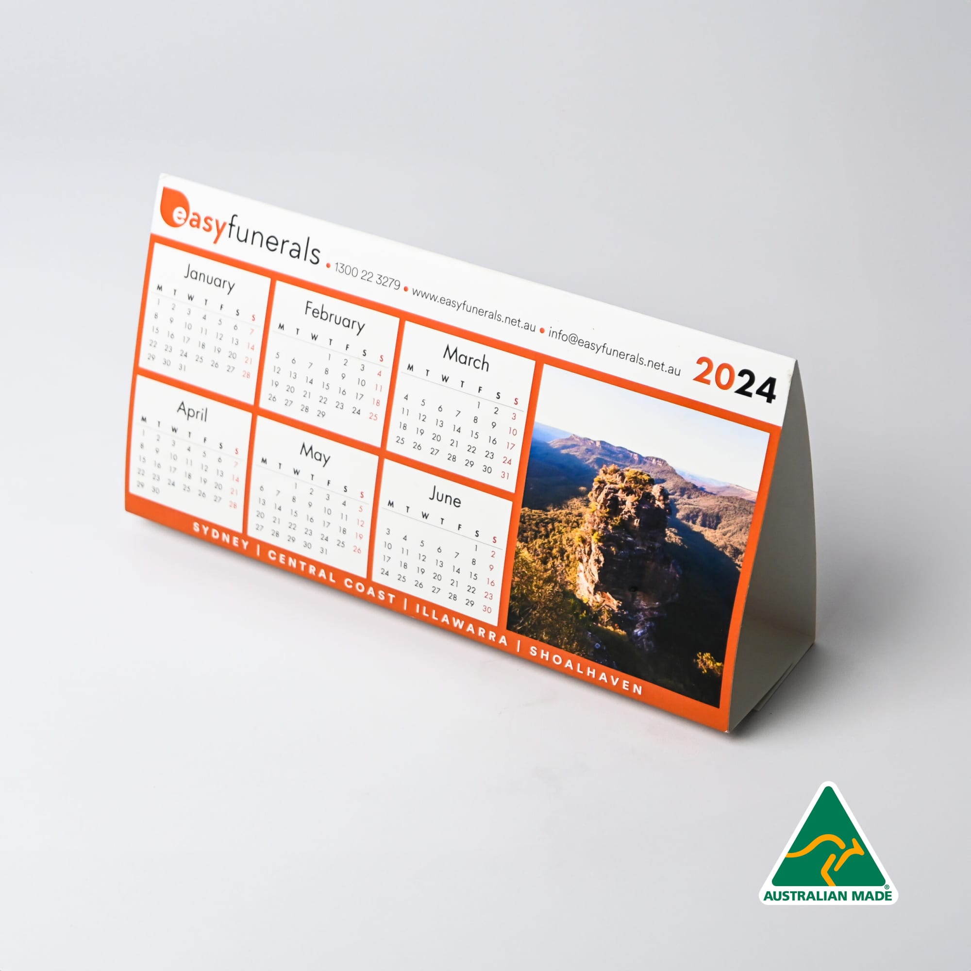 A desk calendar for 2024 with a scenic image, featuring an orange and white design, and a logo. Desk Calendar - Image 1