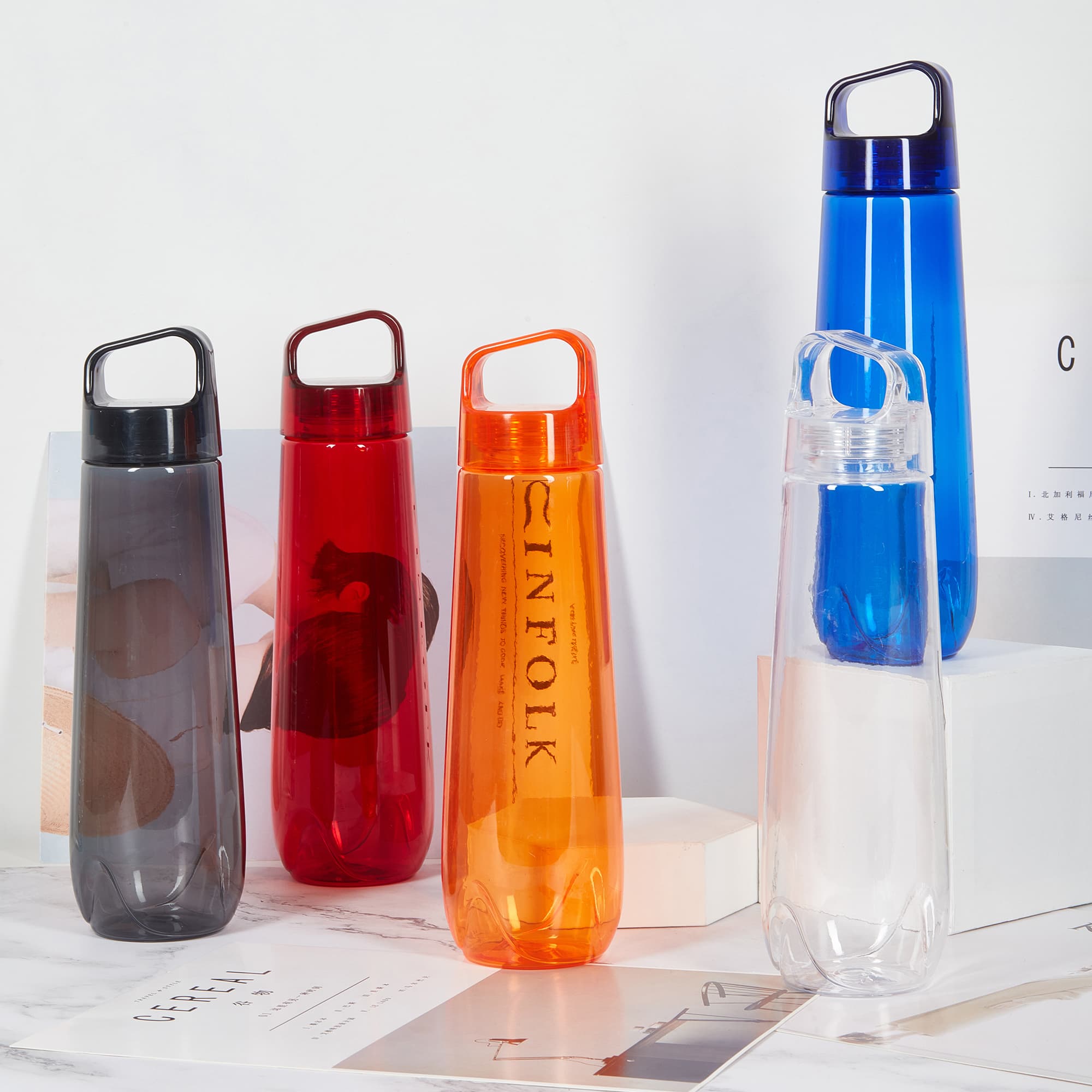 A drink bottle collection featuring blue, orange, red, grey, and clear designs, each with a handle and branding. Sweeta Drink Bottle - Image 1