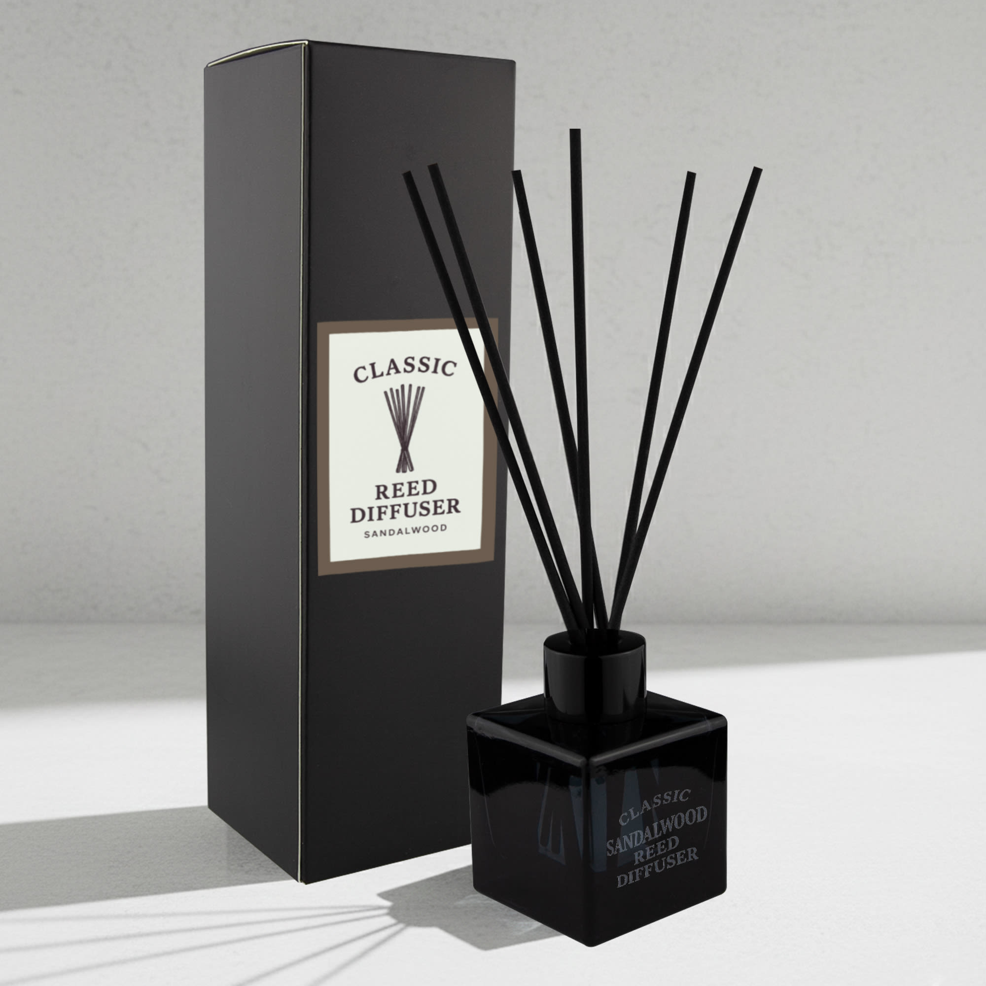 A square black reed diffuser with black reeds, packaged in a matching box, featuring a minimalist design. Classic Reed Diffuser – 50ml Square - Image 1