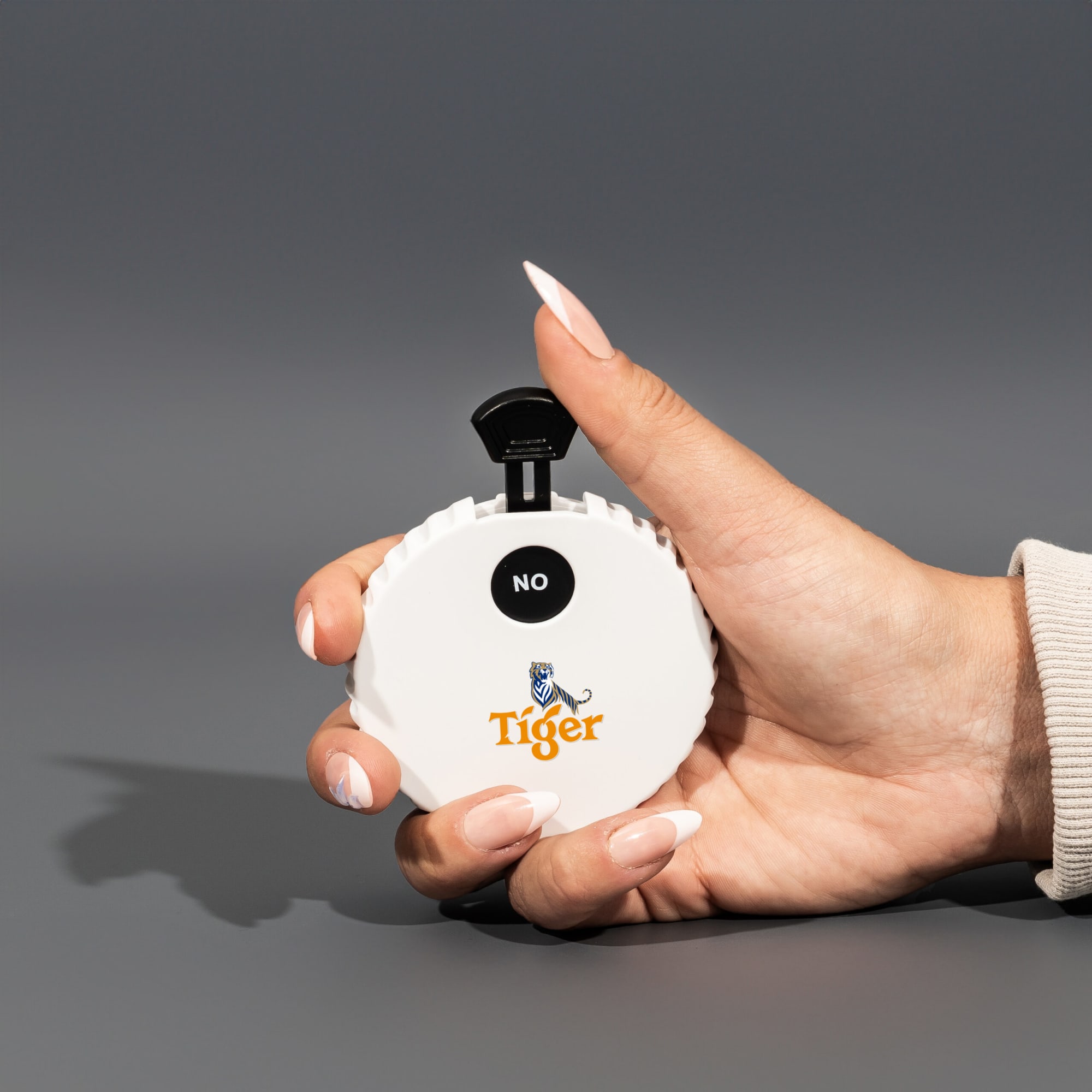A white, circular spinner with a black lever, held in a hand, featuring a logo on the front. Yes, No, Maybe Spinner with Bottle Opener - Image 1