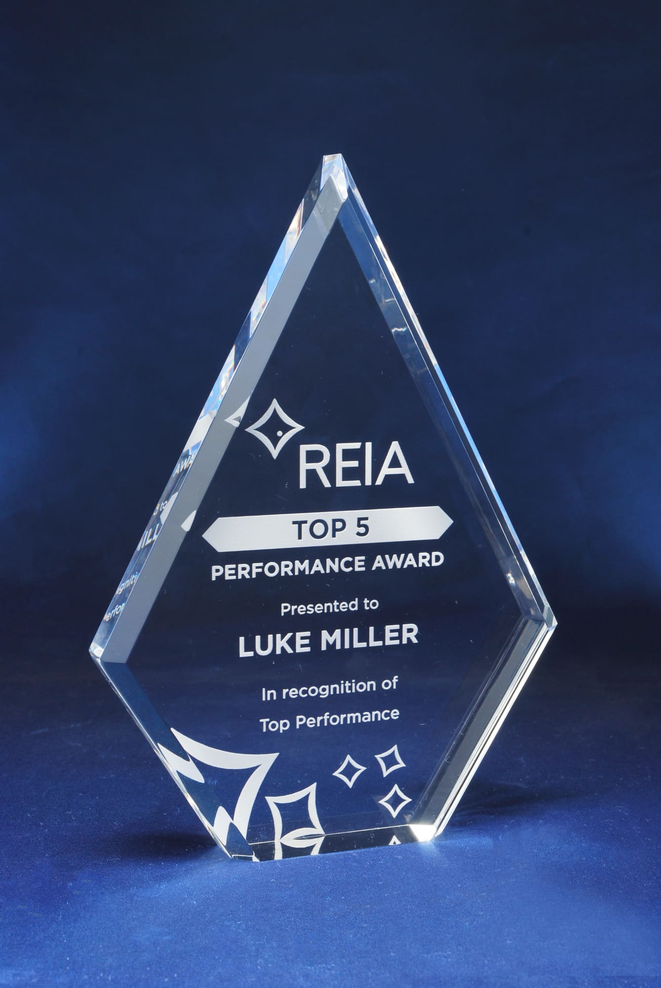 A diamond-shaped clear acrylic trophy with a polished finish, featuring a logo and engraved text. Diamond Acrylic Trophy - Image 1