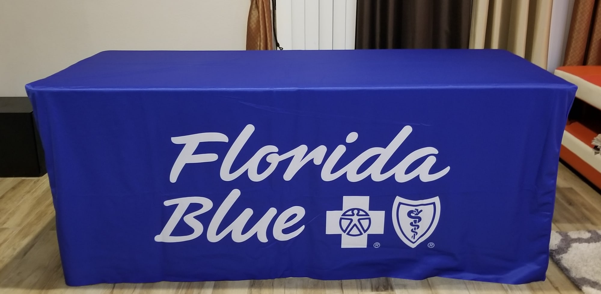A blue fitted table cover featuring a logo and text. Suitable for a 6-foot table. 6 Foot Fitted Table Cover / Table Cloth - Image 1
