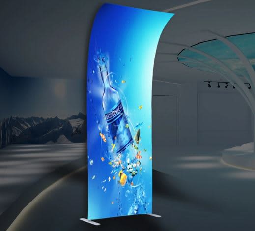 A tension fabric display featuring a vibrant blue design with a water bottle and splashes, set in a modern indoor space. Tension Fabric Display -H-Wave Flat Top 1000mm x 2500mm - Image 1