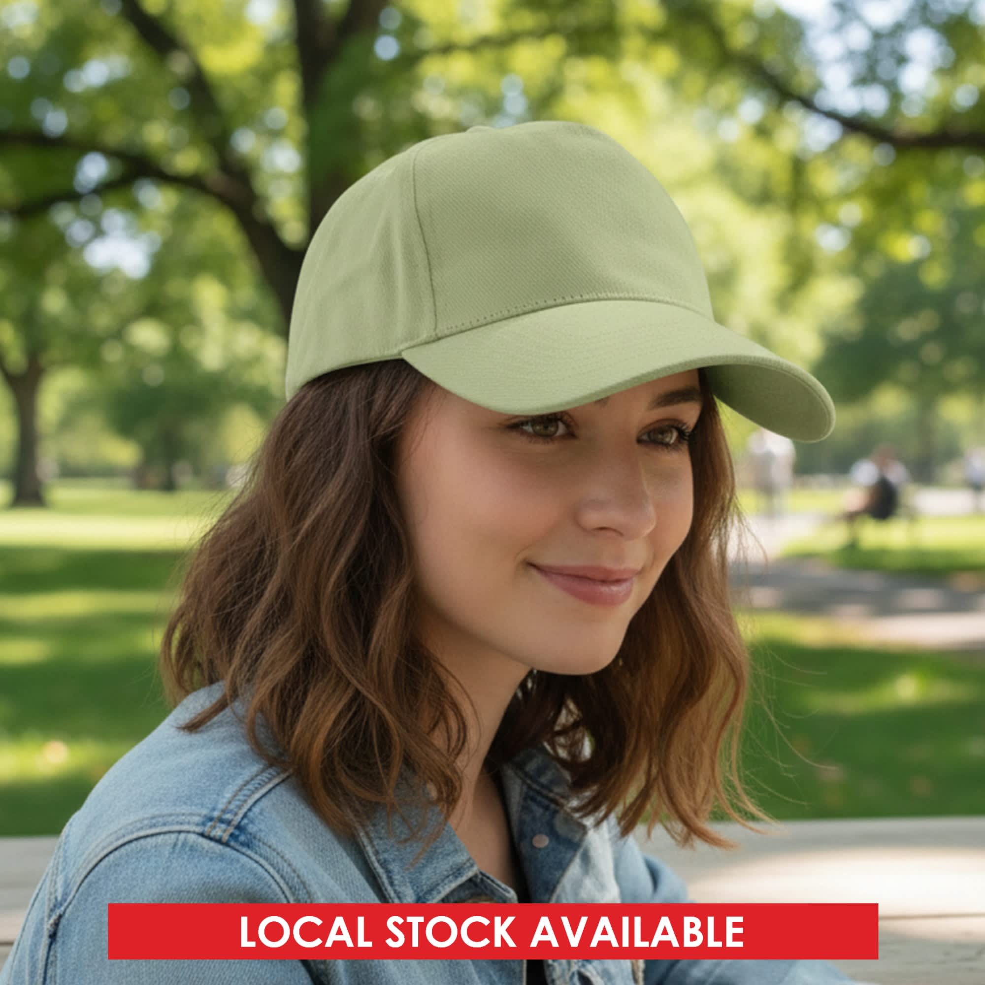 A cap in a light green shade, featuring a curved brim and a logo, worn by a woman in a park setting. Elite Cap - Image 1