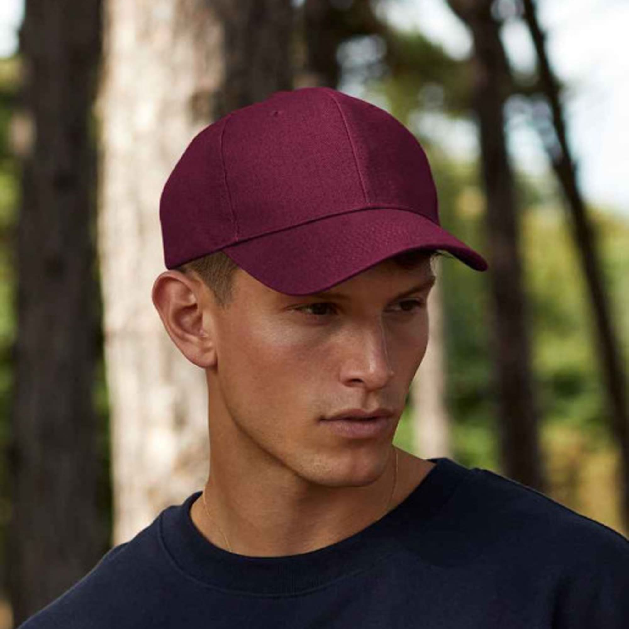 A burgundy six-panel heavy cotton cap on a model, set against a natural outdoor backdrop. Four Seasons 6 Panel Heavy Cotton Cap - Image 1