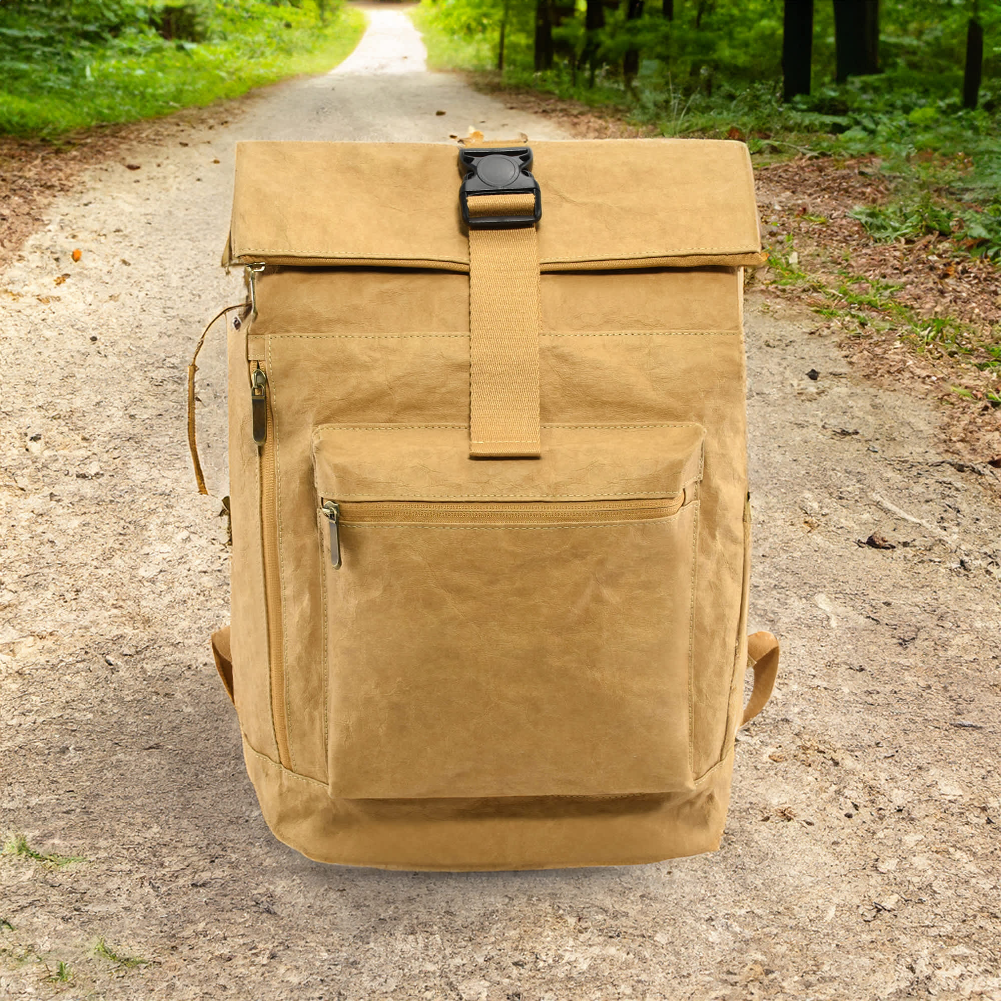 A tan kraft paper laptop backpack with a front pocket and adjustable strap, set on a wooded pathway. Northshore Kraft Paper Laptop Backpack - Image 1