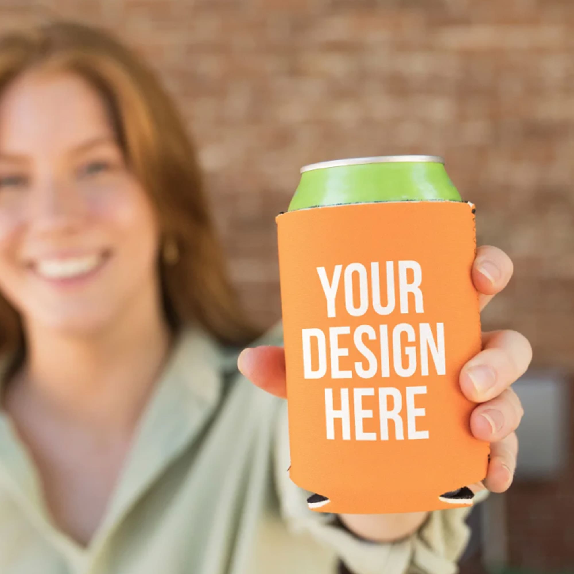 A drink bottle holder in orange, featuring a branding area, presented by a person. Premium Neoprene Stubby Cooler - Image 1