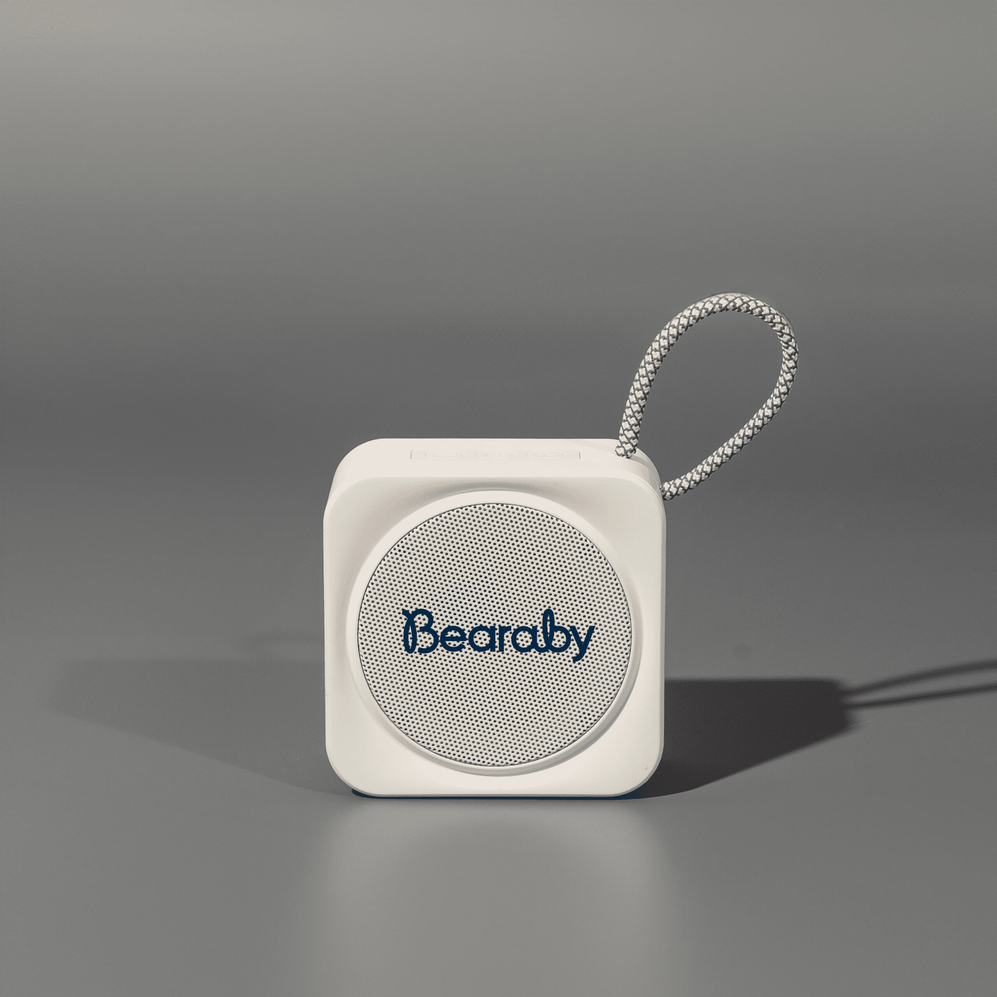A compact white portable Bluetooth speaker with a loop for attachment. Features a logo on the front. Nano Portable BT Speaker - Image 1