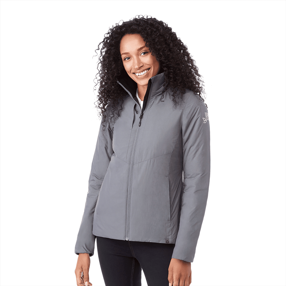 A woman wearing a grey insulated puffer jacket with a zip front and a logo on the sleeve. Kyes Eco Packable Insulated Jacket - Womens - Image 1