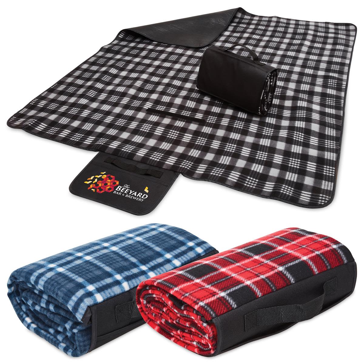 A black and white checkered picnic rug, rolled up with a black strap, alongside blue and red patterned blankets. Picnic Time - Image 1