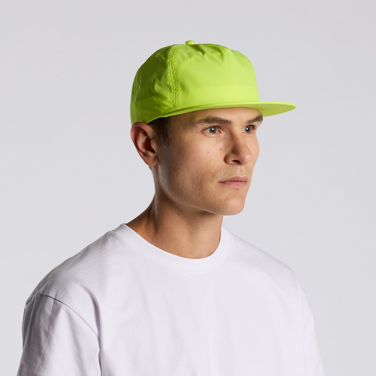 A bright neon yellow cap on a model, featuring a solid design and a logo on the side. Surf Safety Cap - Image 1