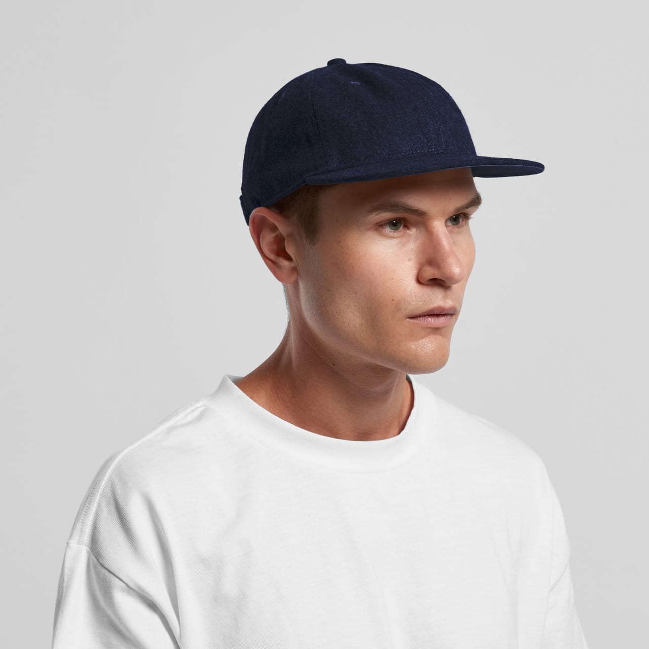 A navy wool cap with a flat brim, worn by a model in a white shirt. The cap features a logo. Class Wool Cap - Image 1