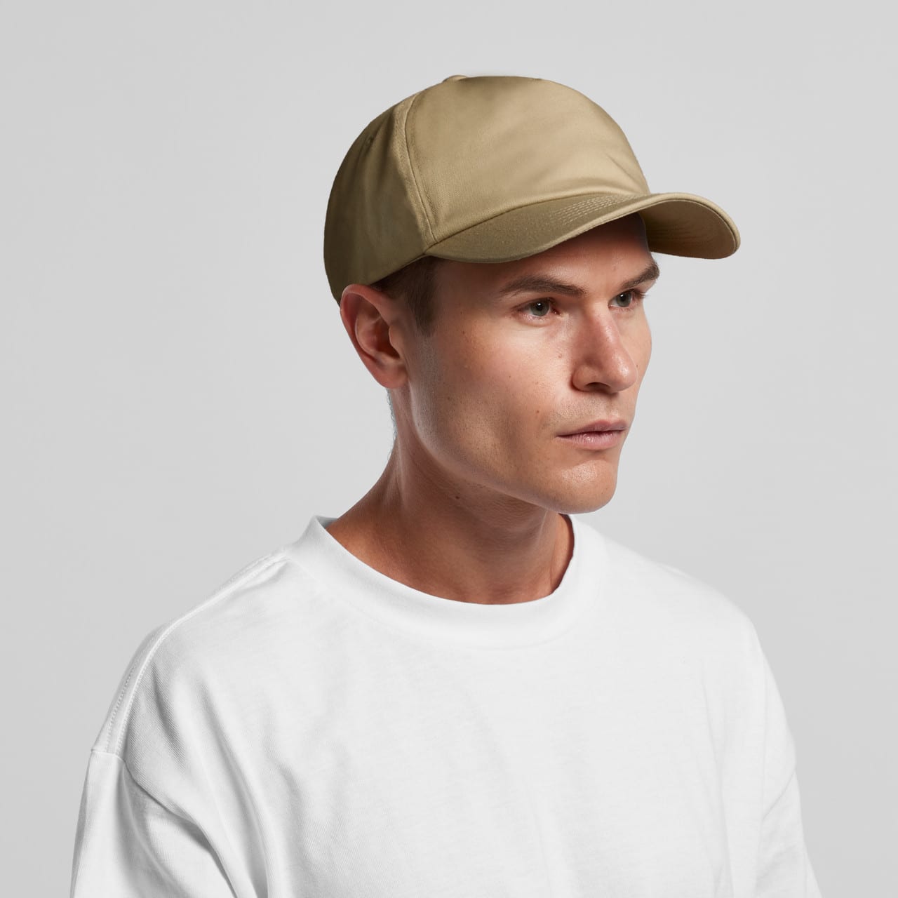 A beige cap is worn by a man with short hair, featuring a curved brim and a logo on the front. Frame Soft Cap - Image 1