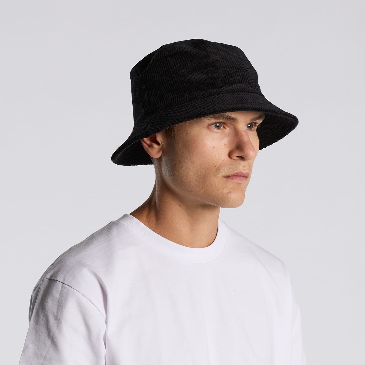 A black cord bucket hat worn by a person in a white t-shirt, featuring a simple, unadorned design. Cord Bucket Hat - Image 1
