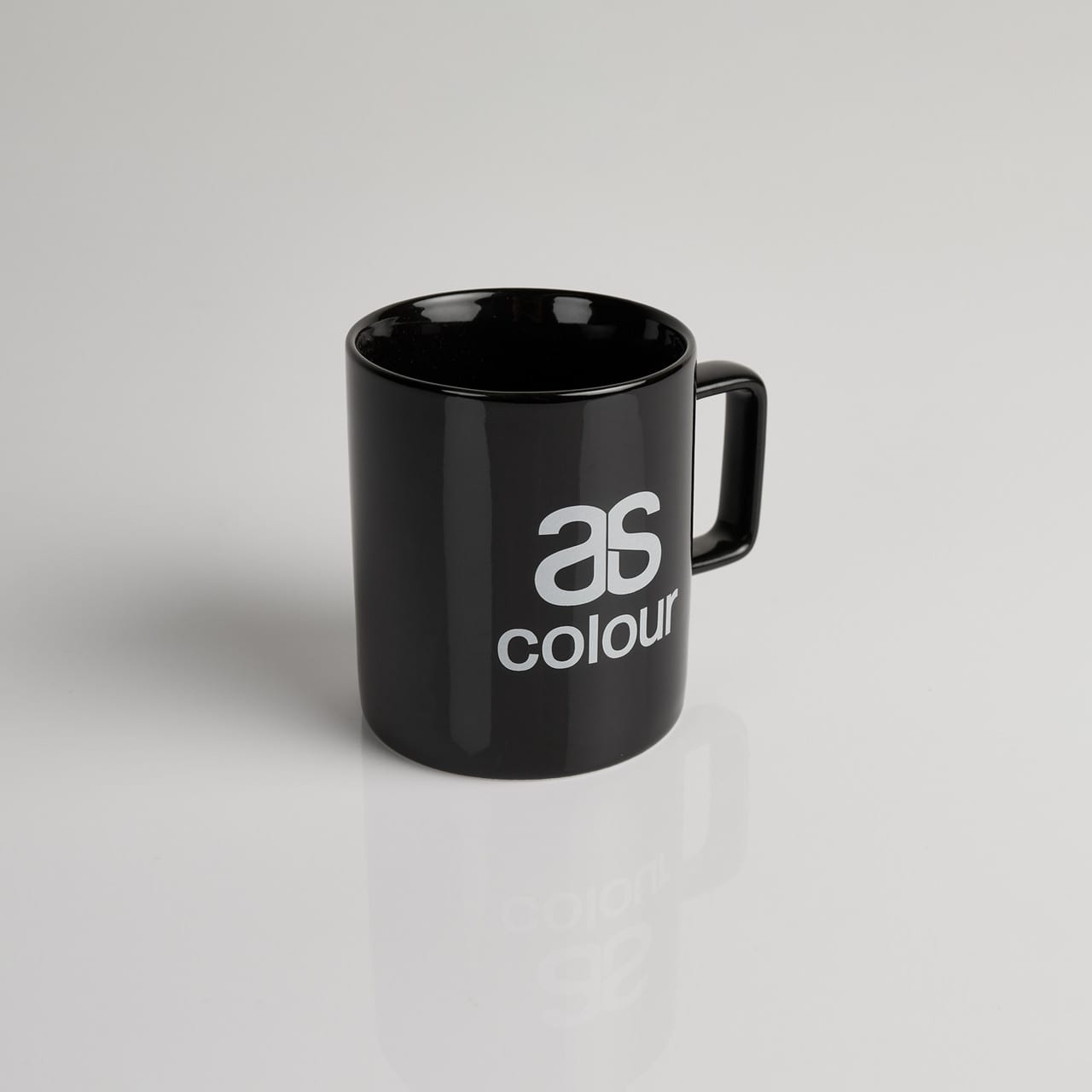 A black coffee mug with a glossy finish and a handle, featuring a logo. ASC Coffee Cup - Image 1