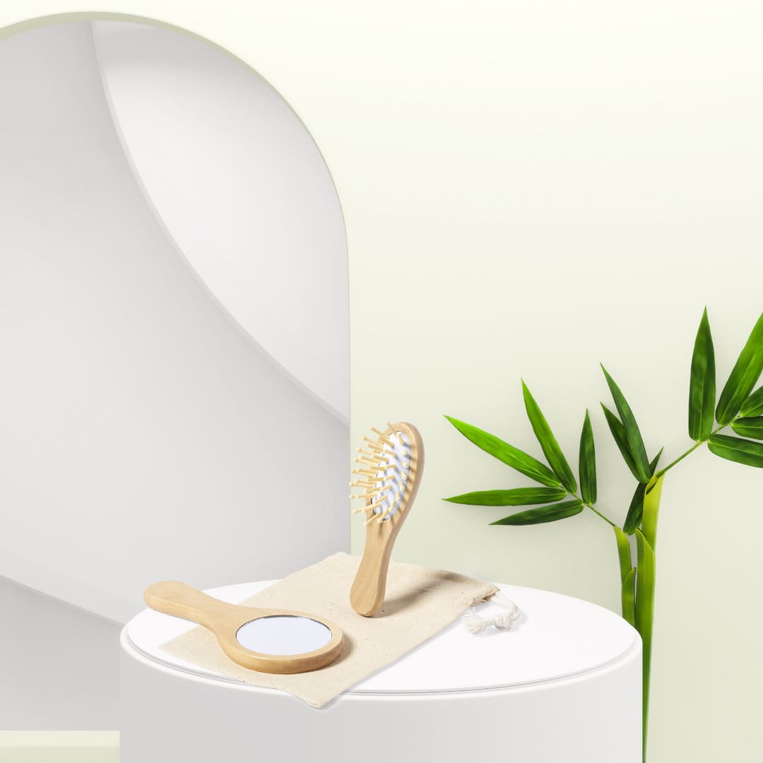 A wooden hairbrush and mirror are placed on a cloth atop a round table, with a green plant in the background. Dianex - Image 1