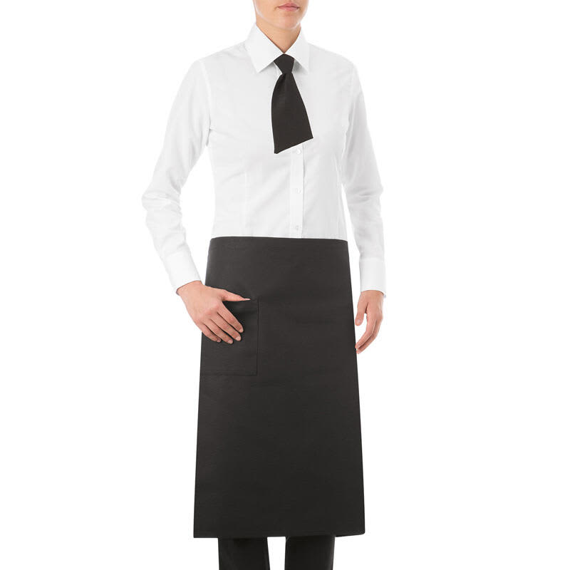 A black apron worn over a white shirt, featuring a pocket and a black tie. The model stands with one hand on the pocket. Praga Apron - Image 1