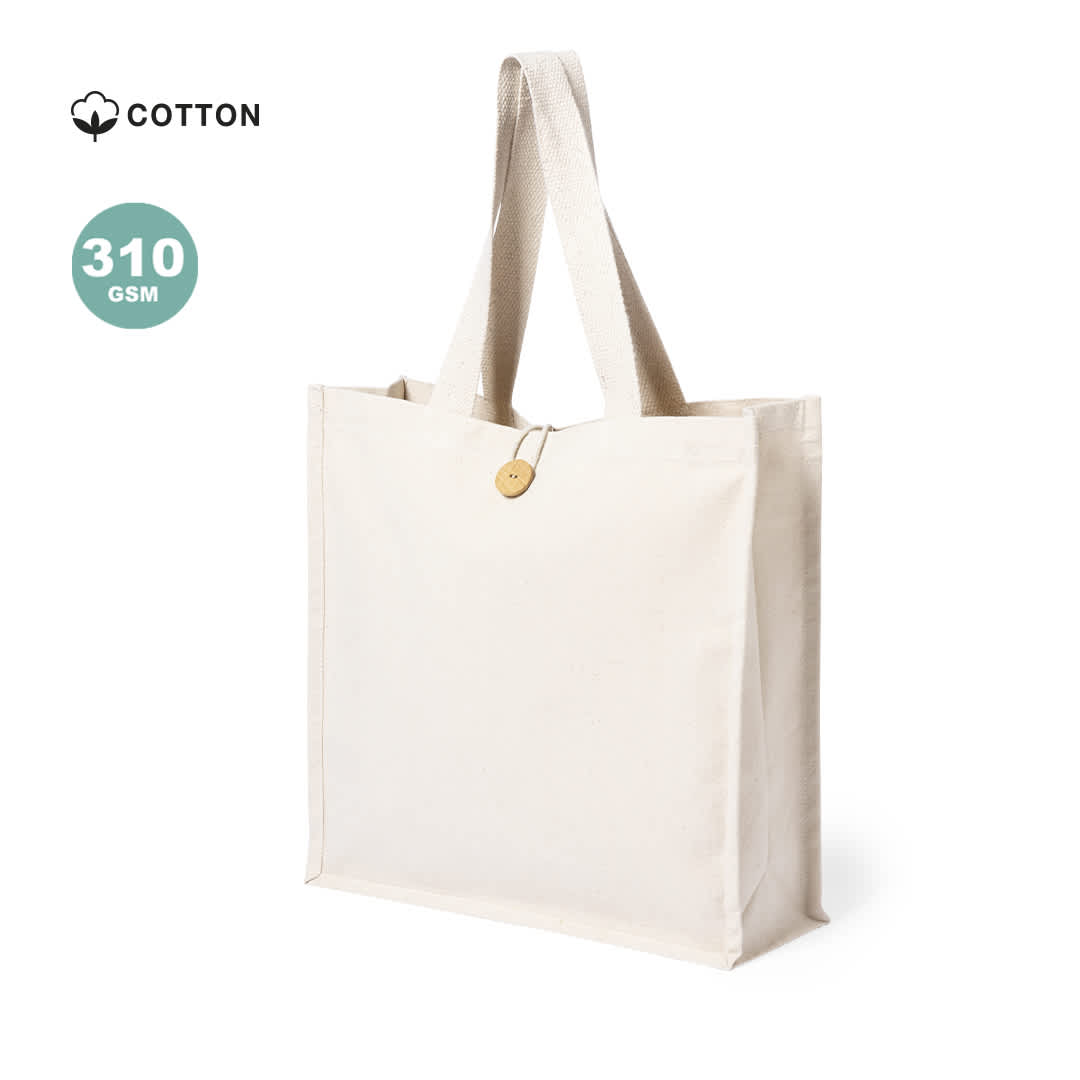 A plain cream tote bag made of cotton, featuring two sturdy handles and a wooden button detail. Sembak Bag - Image 1