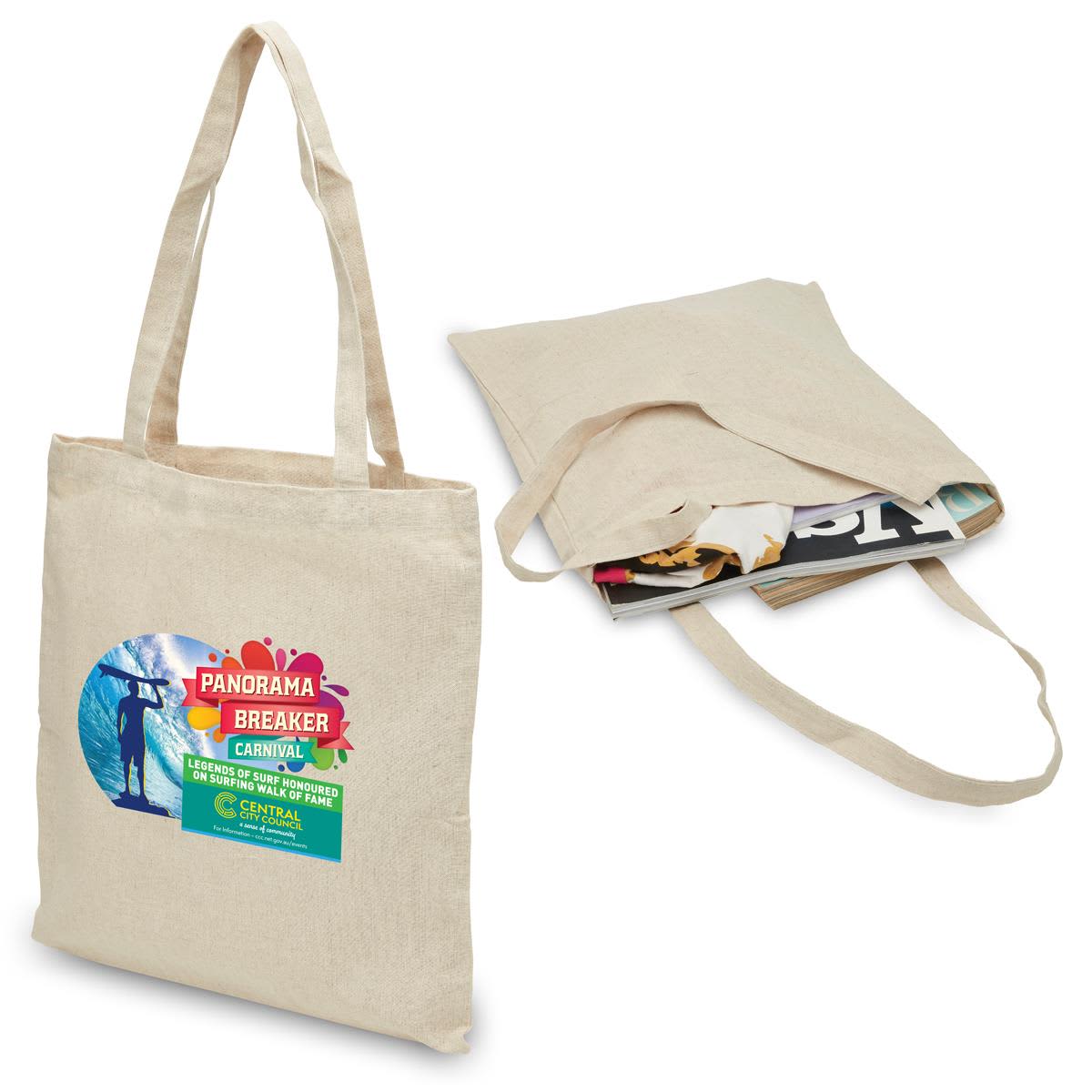 A beige hemp tote bag with two handles, featuring a logo and filled with magazines. Hemp Tote - Image 1