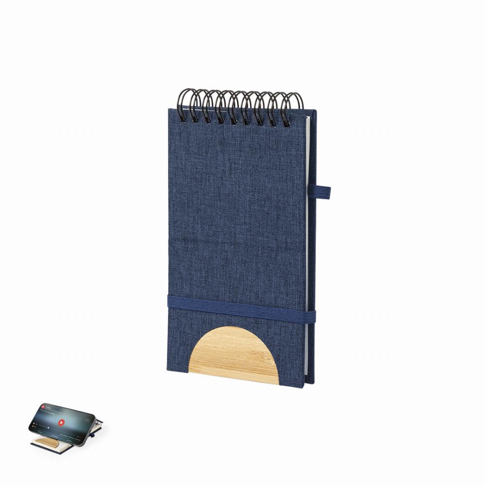 A notebook with a navy fabric cover, spiral binding, and a bamboo accent at the bottom. It features an elastic strap. Alyxa - Image 1