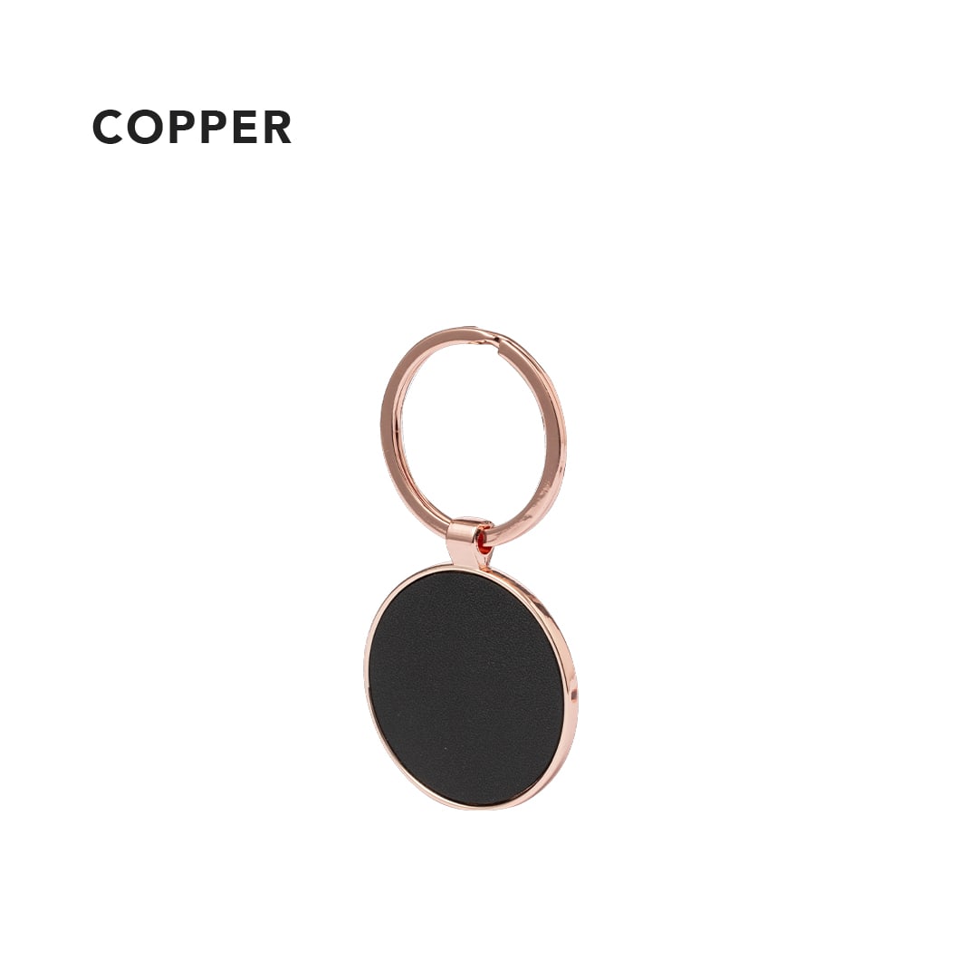 A copper keyring featuring a round pendant with a black surface and a metal loop. Zineth Keyring - Image 1