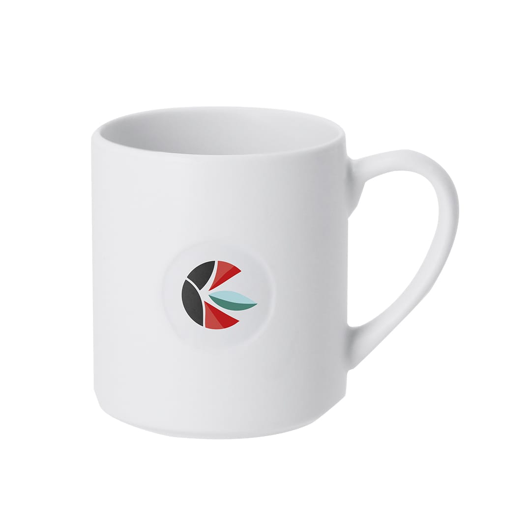 A white coffee mug with a rounded handle and a circular logo featuring black, red, and green elements. Tiraan Mug - Image 1