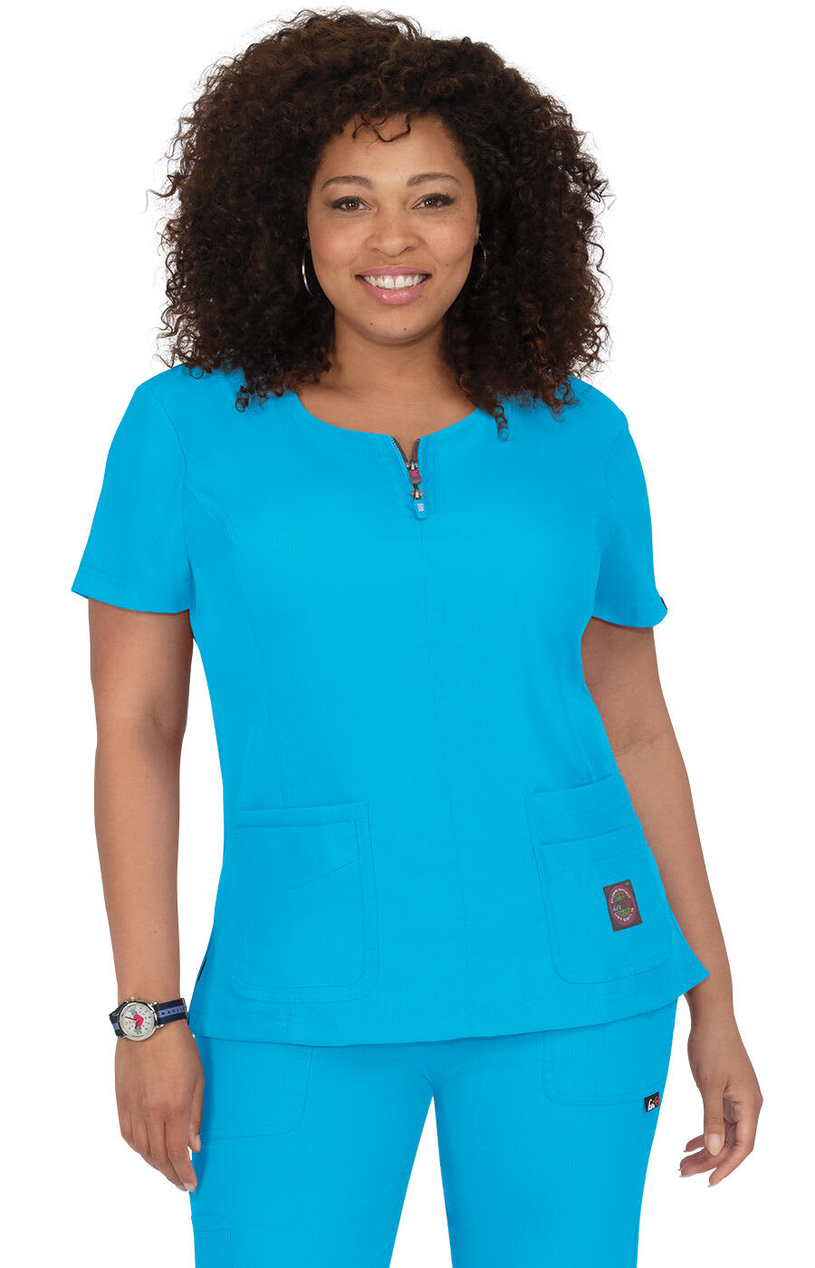 A turquoise medical top with short sleeves, featuring two front pockets and a zip detail. It has a visible logo. Serenity Top - Image 1
