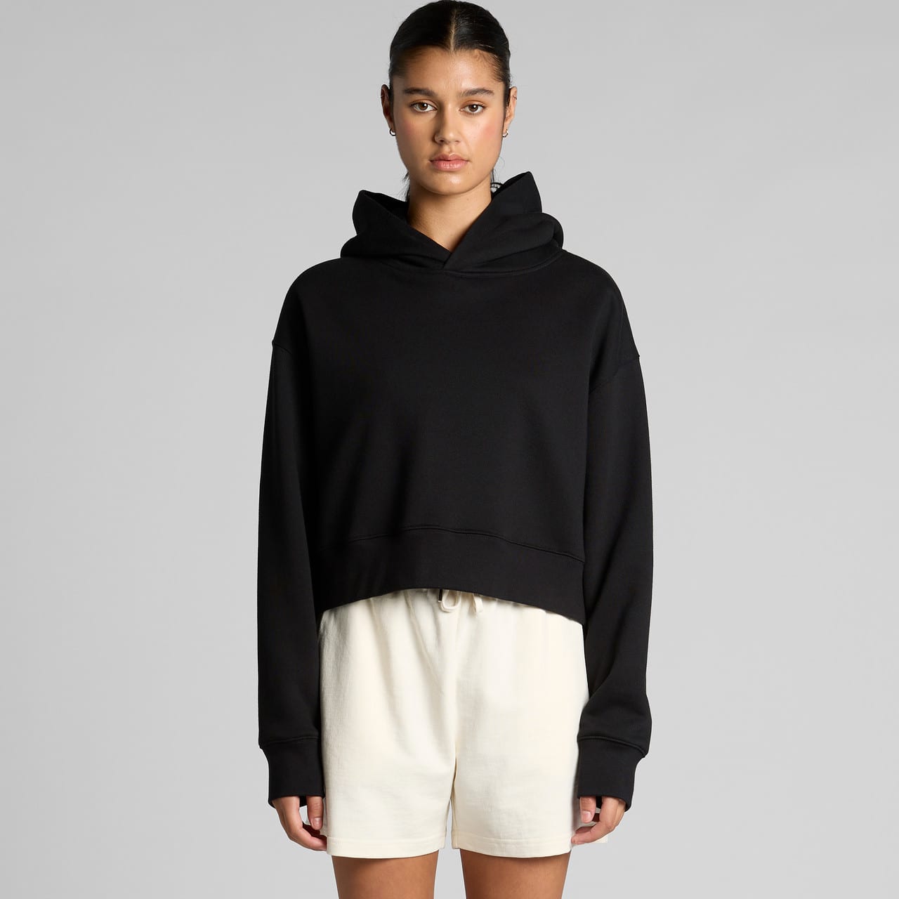A black cropped hoodie with a hood and long sleeves, styled casually with light-coloured shorts. Wo's Relax Crop Hood - Image 1