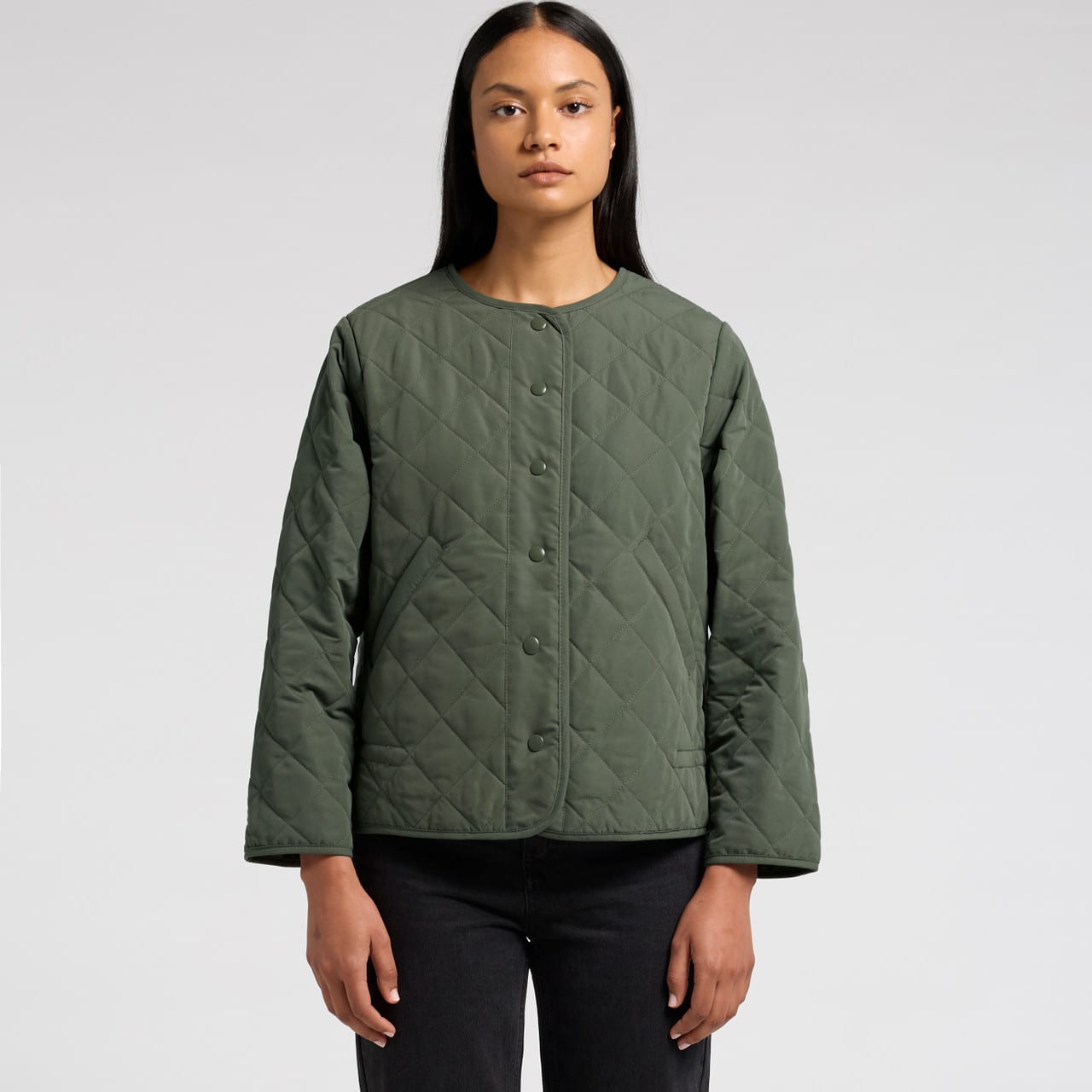 A quilted green jacket featuring a round neckline and button closures, worn by a model. Wo's Quilted Jacket - Image 1