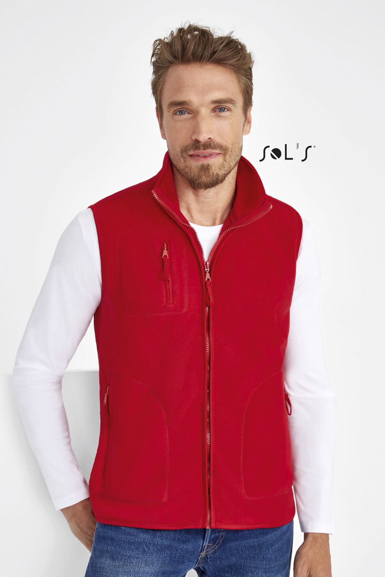 A red unisex fleece vest features a zip front and multiple pockets, displayed on a model. It has a branding logo. Fleece Vest UNISEX NORWAY UNISEX - Image 1