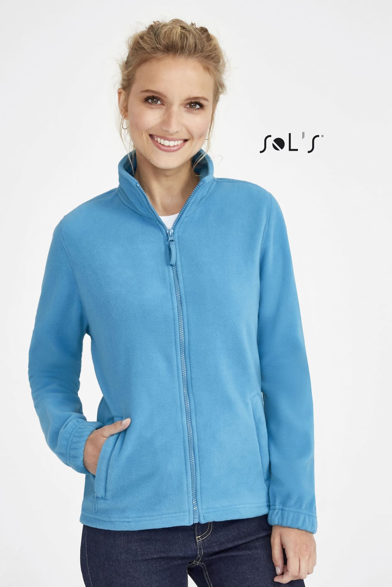 A woman models a zippered fleece top in light blue, featuring a collar and side pockets. The garment has a logo. Fleece top women's zippered NORTH - Image 1