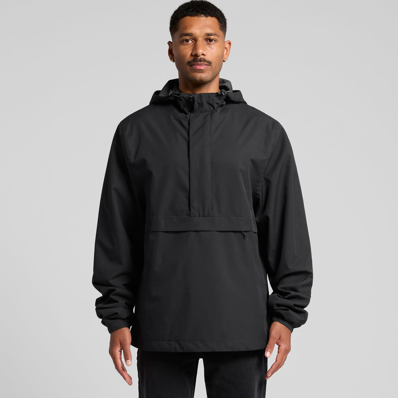 A black windbreaker jacket with a hood and a front pocket, featuring a logo on the front. Tech Windbreaker - Image 1