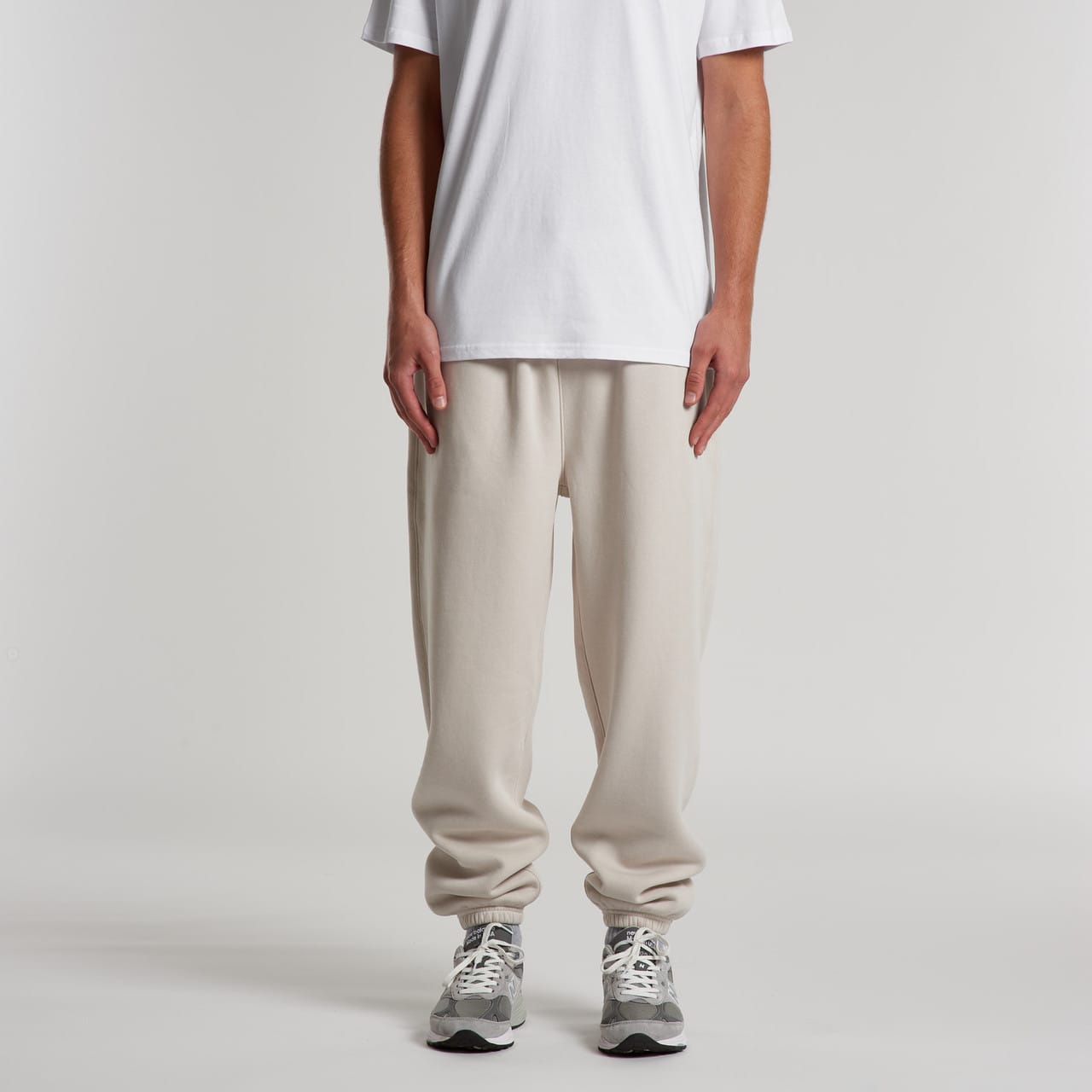 Relax Track Pants in beige, featuring a relaxed fit and elastic cuffs, paired with a plain white t-shirt and sneakers. Relax Track Pants - Image 1
