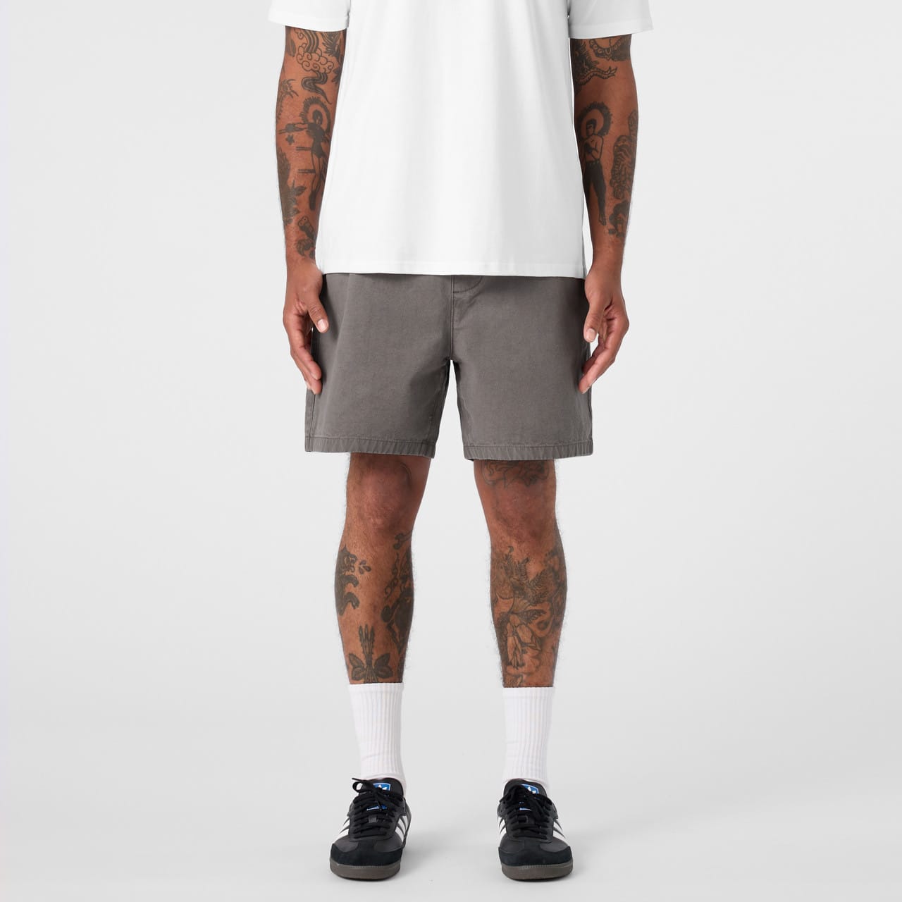 A pair of grey dress shorts featuring a simple design and a logo, modelled by a person with tattoos. Faded Walk Shorts 18" - Image 1