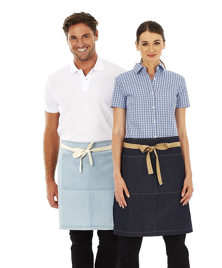 A denim and light denim waist apron worn by a man and woman, both styled casually. The aprons feature a tied belt and pockets. Charlie - Waist Apron - Image 1