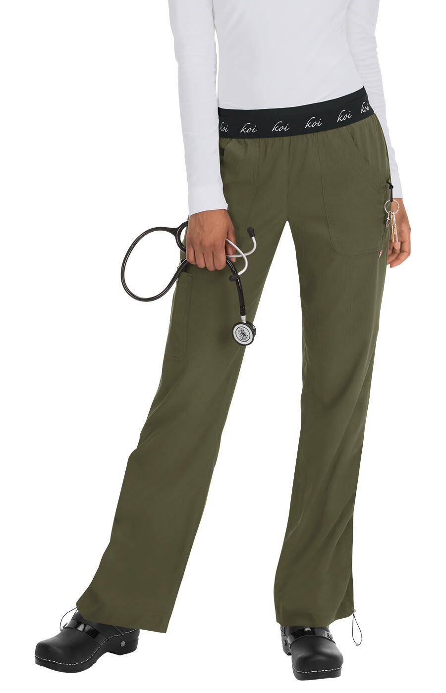 A pair of olive green scrubs with a black waistband, featuring a logo, held by a person with a stethoscope. Spirit Pant - Image 1